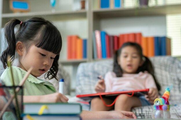 Een mooie Aziatische moeder die bezig is met wfh terwijl ze haar kinderen thuis verzorgt en onderwijst.