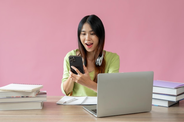 Een mooie Aziatische studente kijkt met een verrassend gezicht naar haar smartphonescherm