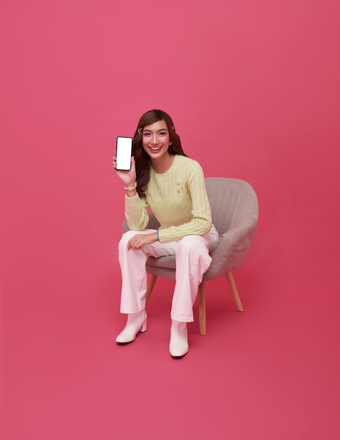 Een mooie Aziatische tienervrouw die een smartphone gebruikt en op een stoel zit.