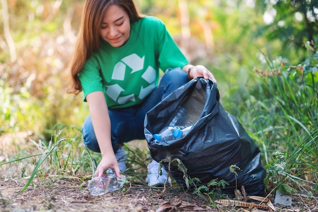 Een mooie aziatische vrouw die plastic afvalflessen oppakt in een doos en zak voor recyclingconcept