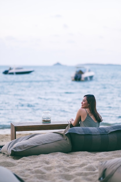 Een mooie Aziatische vrouw geniet van het zitten en ontspannen op het strand aan de kust