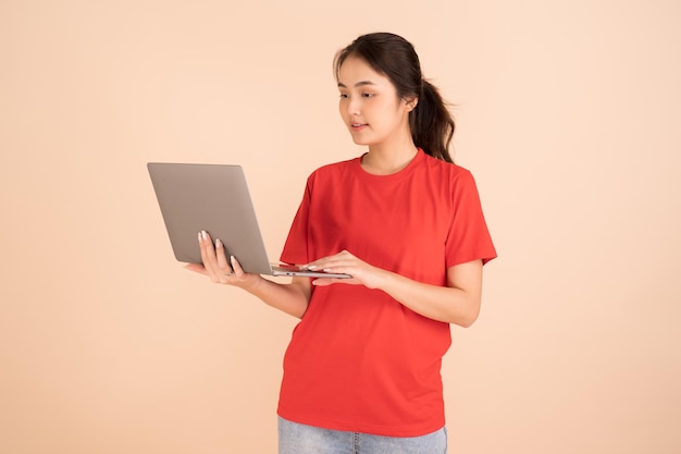 Een mooie Aziatische vrouw in een rood shirt houdt een laptop vast