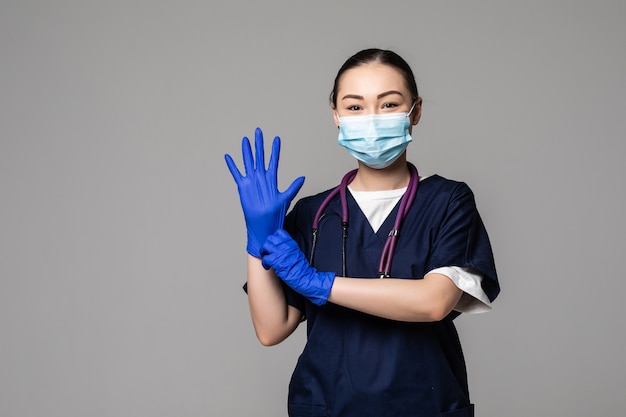 Een mooie Aziatische vrouwelijke arts die een blauw masker en handschoenen draagt om infectie te voorkomen