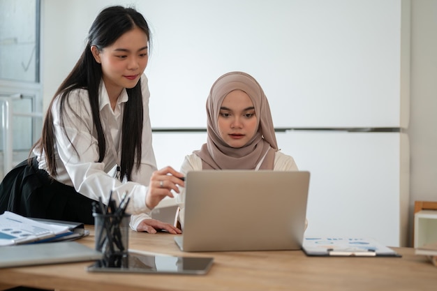 Een mooie Aziatische zakenvrouw en een professionele Aziatische moslimzakenvrouw werken samen