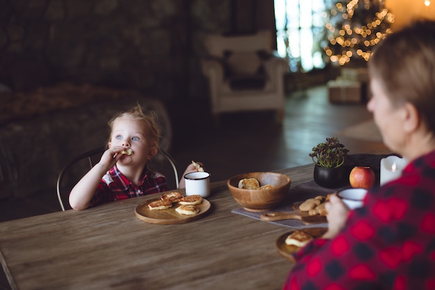 Een mooie baby heeft ontbijt met pannenkoeken van kwark en cacao