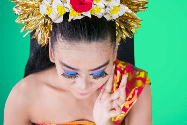 Een mooie Balinese danseres die make-up op haar gezicht doet.