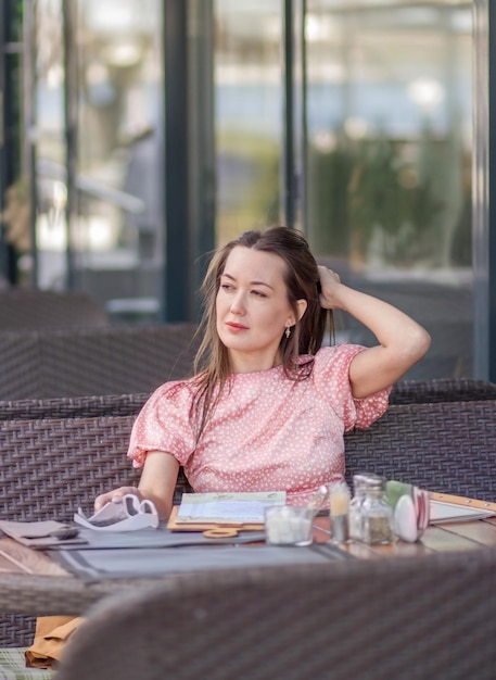 Een mooie brunette straigt haar haar met haar handen in de middag op straat tijdens