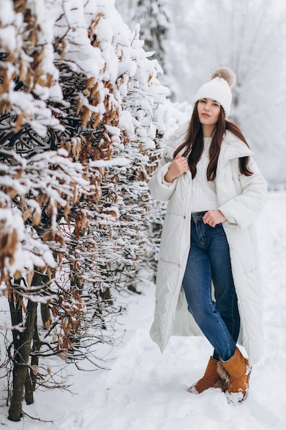 Een mooie en mode vrouw in witte warme kleding lopen in besneeuwde weer.