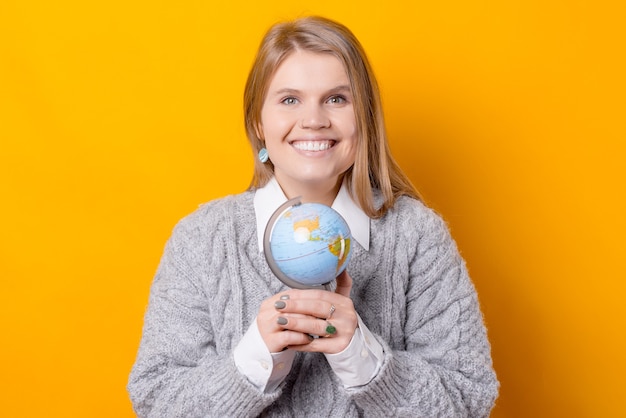 Een mooie foto van een vrouw die met beide handen een wereldbol vasthoudt en glimlacht, is op zoek