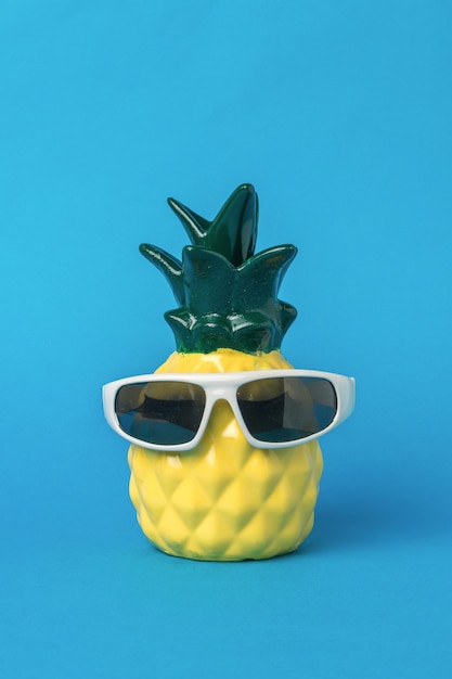 Een mooie gele ananas met bril op een blauwe achtergrond. Zomer concept.