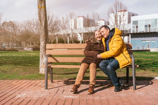 Een mooie gelukkige senior paar zittend op een bankje in het park op een zonnige winterdag