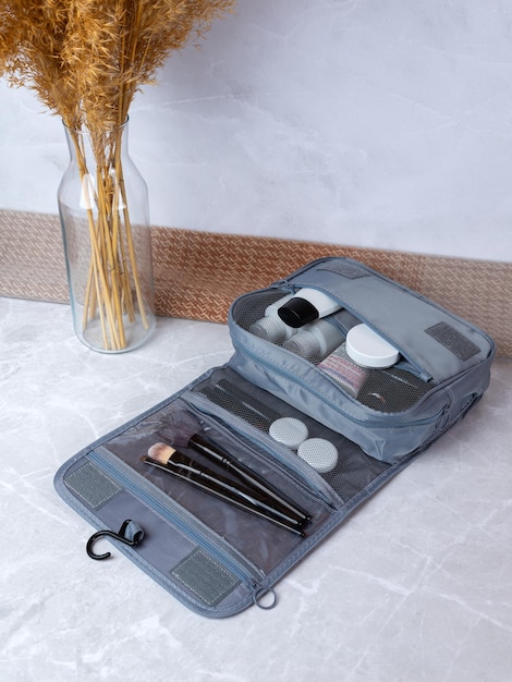 Een mooie grijze make-up tas met de nodige producten voor de verzorging van de vrouwenhuid Cosmetica shampoo crèmes make-up kwasten in een make-up tas tegen de achtergrond van een mooie dameskamer