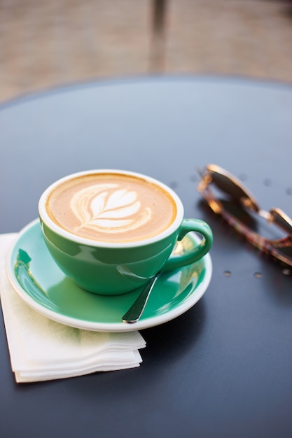 Een mooie groene kop cappuccino met trendy latte art in de tafel