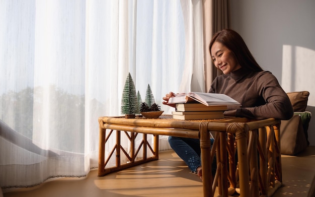 Een mooie jonge Aziatische vrouw die thuis een boek leest
