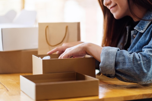 Een mooie jonge aziatische vrouw die thuis een postpakketdoos ontvangt en opent voor bezorging en online winkelconcept