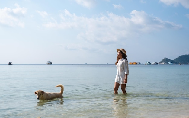 Een mooie jonge Aziatische vrouw en een hond die samen in de zee spelen