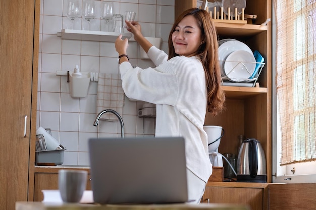 Een mooie jonge Aziatische vrouw freelancer die een laptop gebruikt om thuis online in de keuken te werken