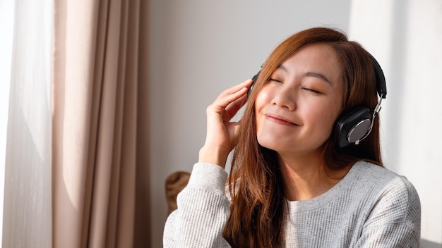 Een mooie jonge aziatische vrouw luistert thuis graag naar muziek met een koptelefoon