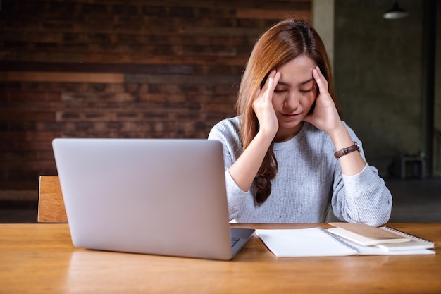 Een mooie jonge Aziatische vrouw raakt gestrest tijdens het werken op een laptopcomputer