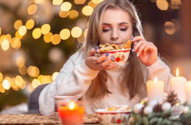 Een mooie jonge blonde vrouw proeft verse kerstpeperkoek met veel smaak