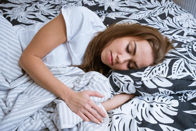 Een mooie jonge brunette vrouw wordt's morgens wakker terwijl