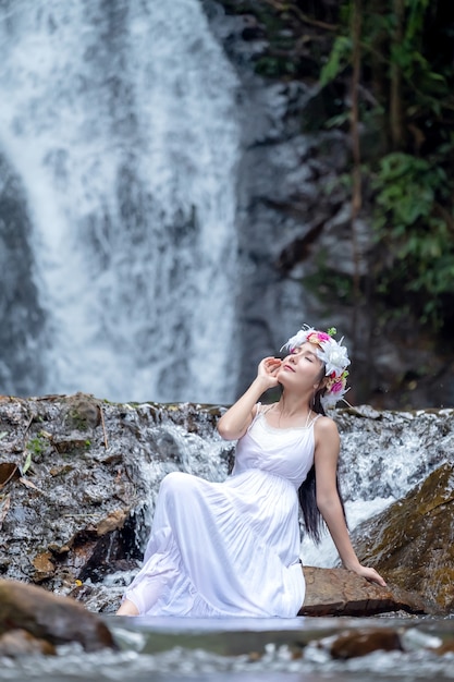 Een mooie jonge dame ontspant in de natuur in de buurt van een waterval.