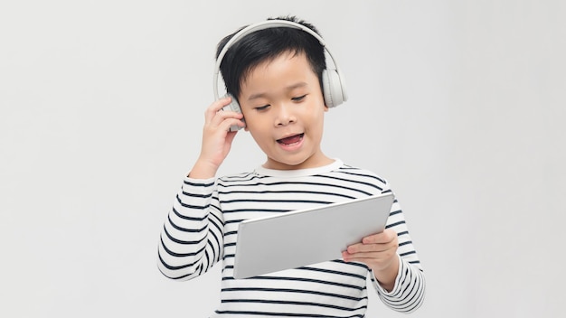 Een mooie jonge leerling die zich verheugt en springt met zijn tablet met een koptelefoon op en glimlacht