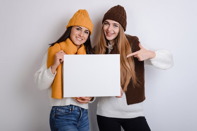 Een mooie jonge student meisjes met houdt een wit vierkant blanco vel in haar handen.