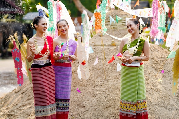 Een mooie jonge Thaise dame in een traditionele Thaise jurk staat en praat op een hoop zand in de tempel.