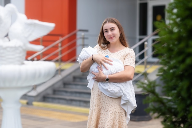 een mooie jonge vrouw die onlangs is bevallen van een baby houdt hem gelukkig in haar armen