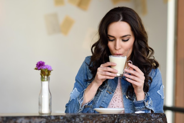 Foto een mooie jonge vrouw drinkt koffie in een café.