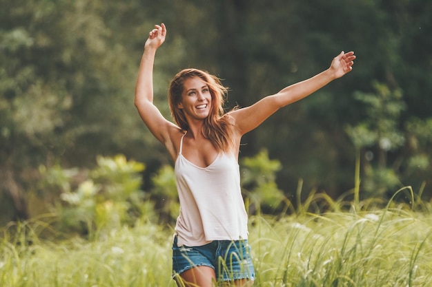 Een mooie jonge vrouw geniet van de zomer, ontspant en rent in de natuur omzoomd met een weelderig landschap.