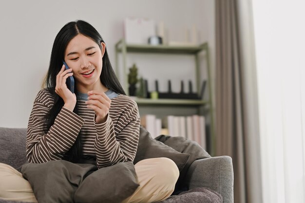 Een mooie jonge vrouw heeft een telefoongesprek op de bank thuis.