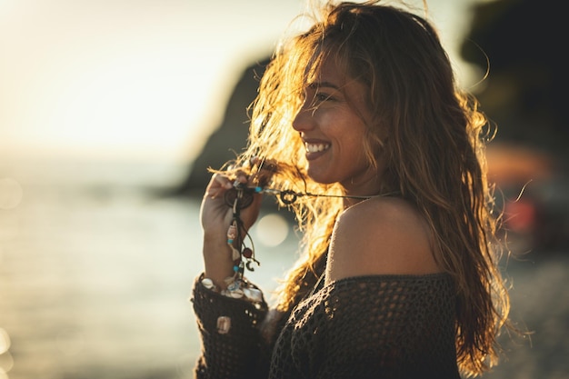 Een mooie jonge vrouw heeft plezier en ontspant op het strand bij de zonsondergang.