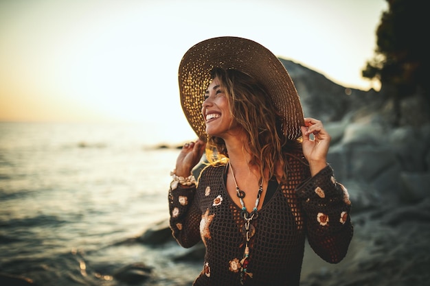 Een mooie jonge vrouw heeft plezier en ontspant op het strand bij de zonsondergang.