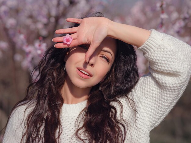 Een mooie jonge vrouw in de buurt van een bloeiende lente kersenbloesem boom. Het idee en concept van vernieuwing, zelfzorg, gezondheid en geluk, Japanse stijl