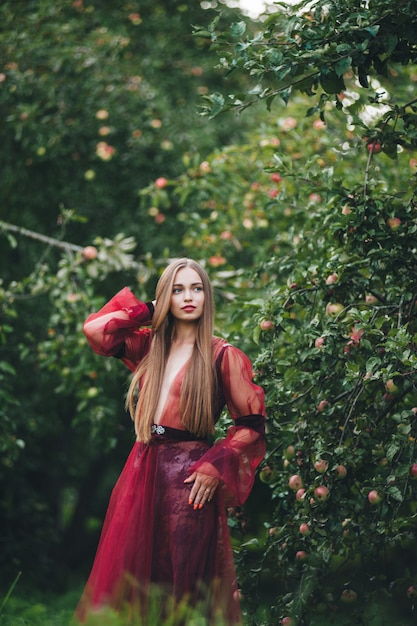 Een mooie jonge vrouw in een bard-jurk staart in het veld en de tuin.