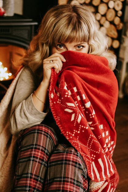 Een mooie jonge vrouw in een rode ruit zit in een warm klassiek nieuwjaarsinterieur