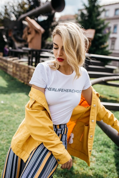 Een mooie jonge vrouw met blond haar zit in het park.
