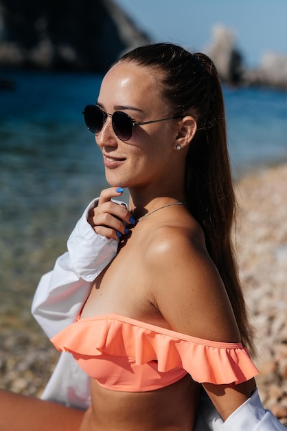 Een mooie jonge vrouw met een bril en een bikini zit op de oceaan en geniet van een vakantie op een zonnige dag Toerisme en toeristische reizen Grenzen en vakantie openen