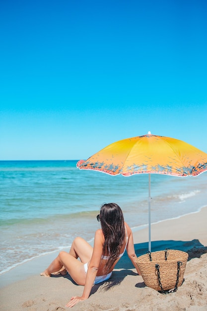 Een mooie jonge vrouw ontspant zich op een tropisch strand met wit zand.