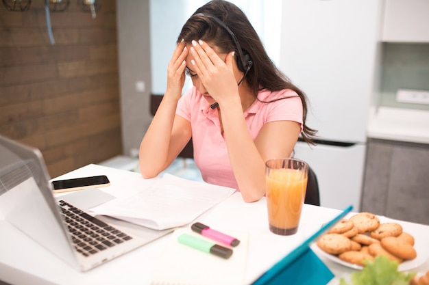 Een mooie jonge vrouw werkt in de keuken van haar huis, ze is erg moe.