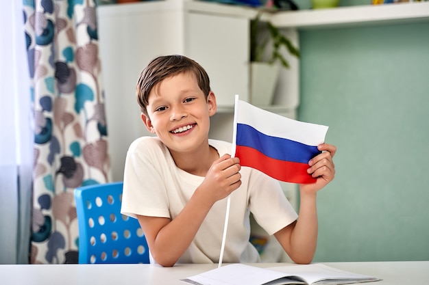 Een mooie jongen met de vlag van de dag van Rusland