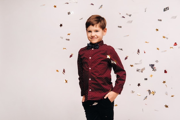 Een mooie jongen staat op en confetti valt op hem op een grijze achtergrond