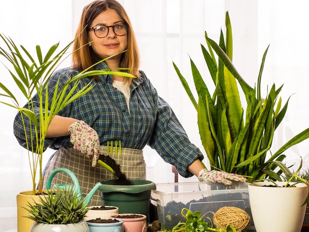 Een mooie meid bloemist plant kamerplanten in nieuwe potten een meisje zorgt voor planten een vrouw plant kamerplanten