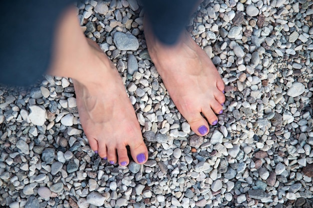 Een mooie meisjesvoeten bij het strand paarse nagellak