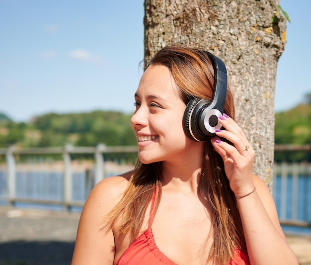 Een mooie Spaanse vrouw die op een zonnige dag aan de kust naar muziek luistert