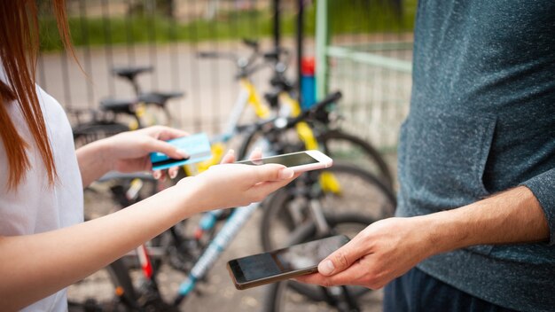 Een mooie vrouw betaalt een fietshuur met een telefoon en een bankkaart. mobiele betaling. Huur een fiets voor een dag. Technologie, internet, smartphone