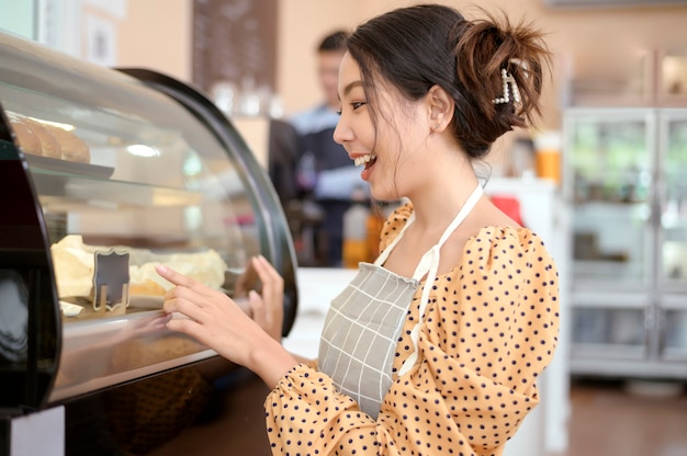 Een mooie vrouw die een bakkerij of coffeeshop heeft, lacht in haar winkel