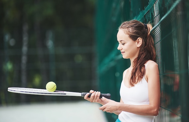 Een mooie vrouw die een bal van het sportkledingtennis draagt.